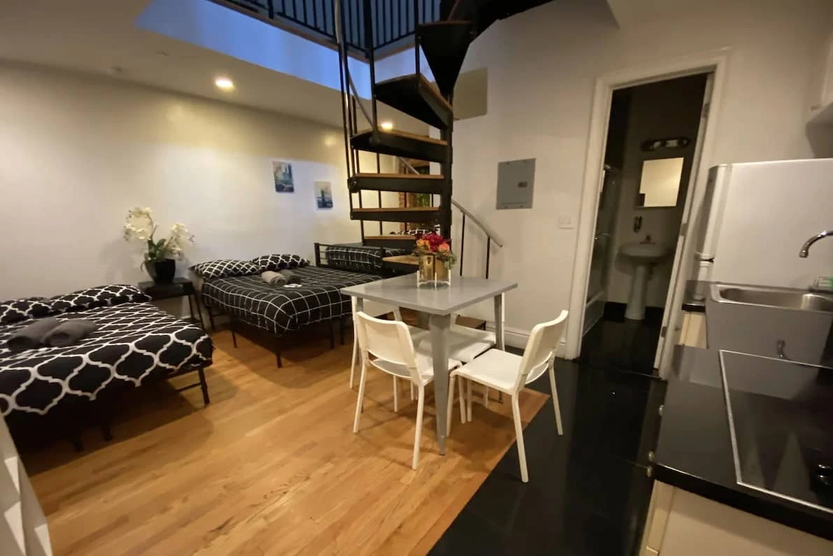 Apartamento con camas, mesa de comedor y escalera de caracol