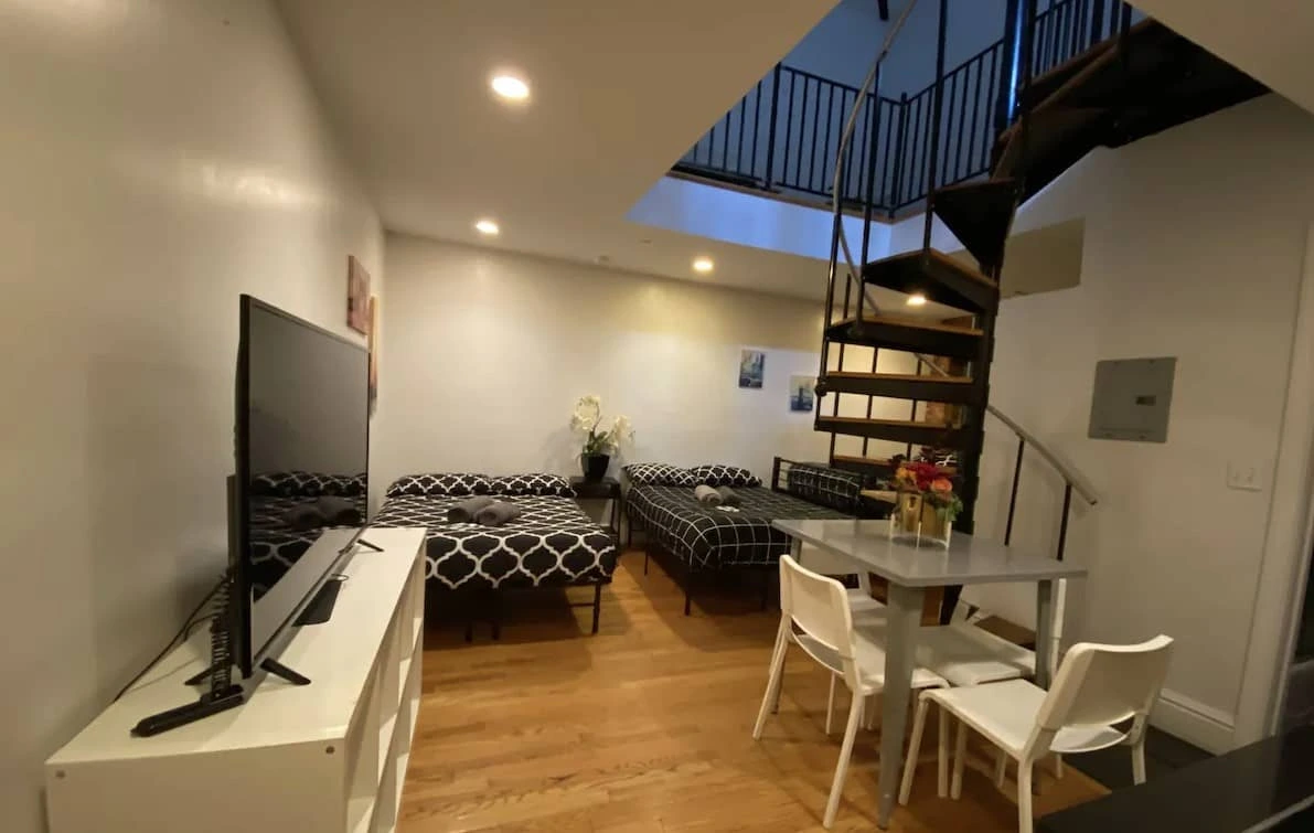 Sala con televisor, mesa y escalera de caracol en un apartamento del hotel